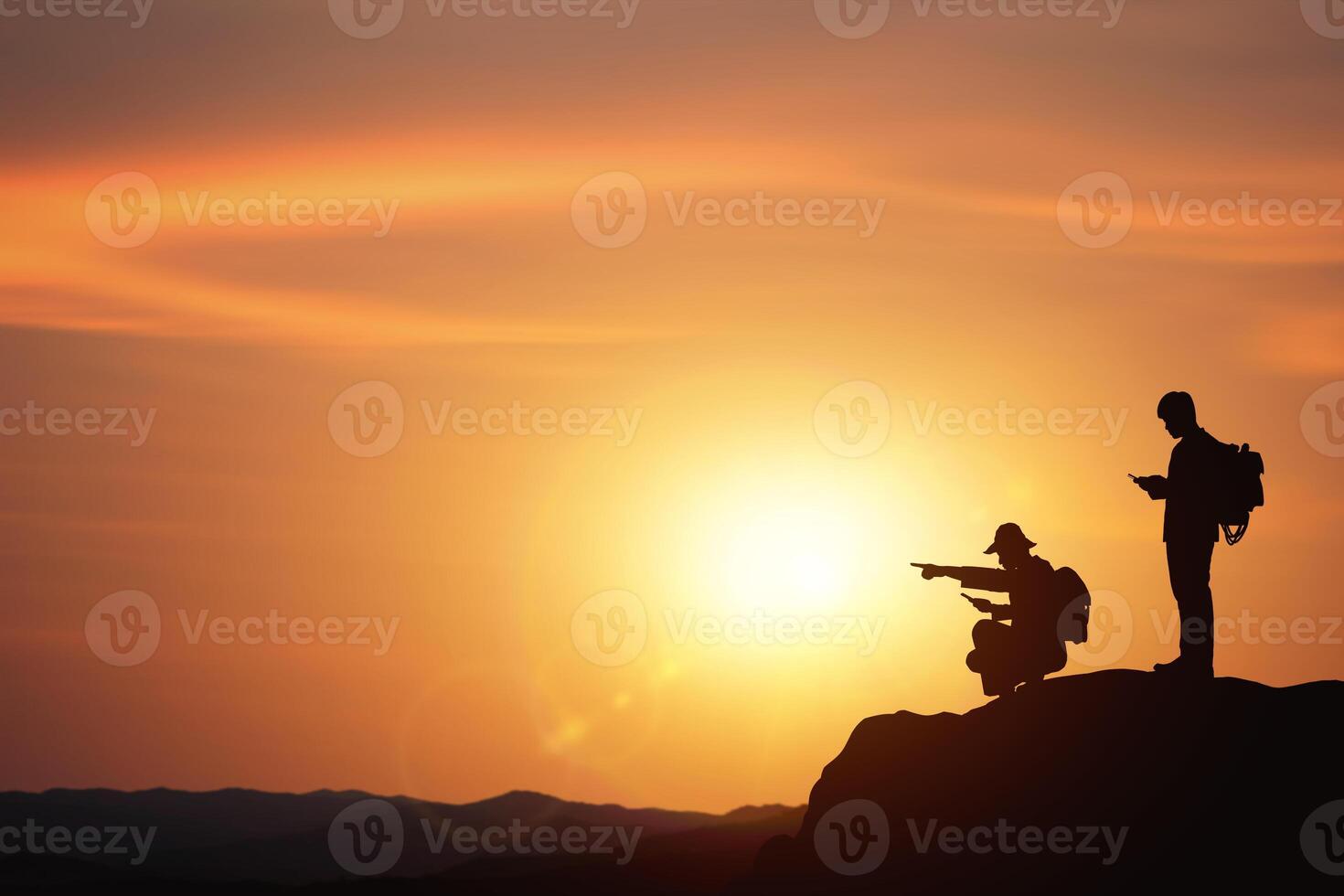 Planning and direction setting ideas. business concept with silhouettes of two businessmen planning trip on mountain with sunset background. photo