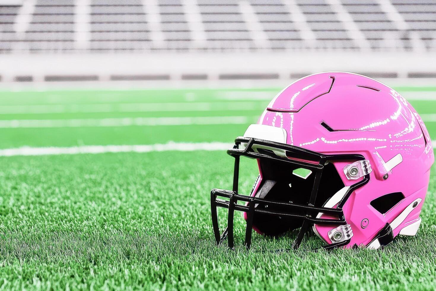 Pink football helmet on green grass field at empty stadium photo
