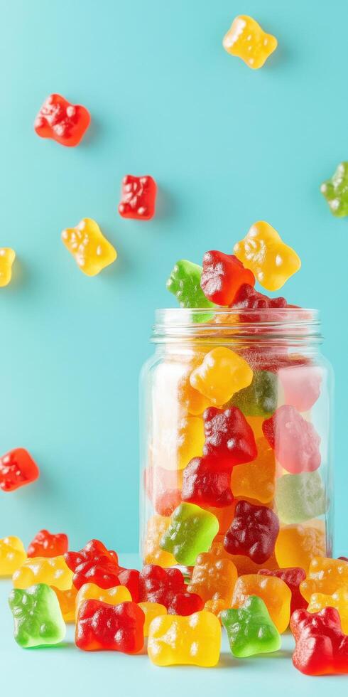Colorful gummy bears in jar with scattered candies on blue background photo