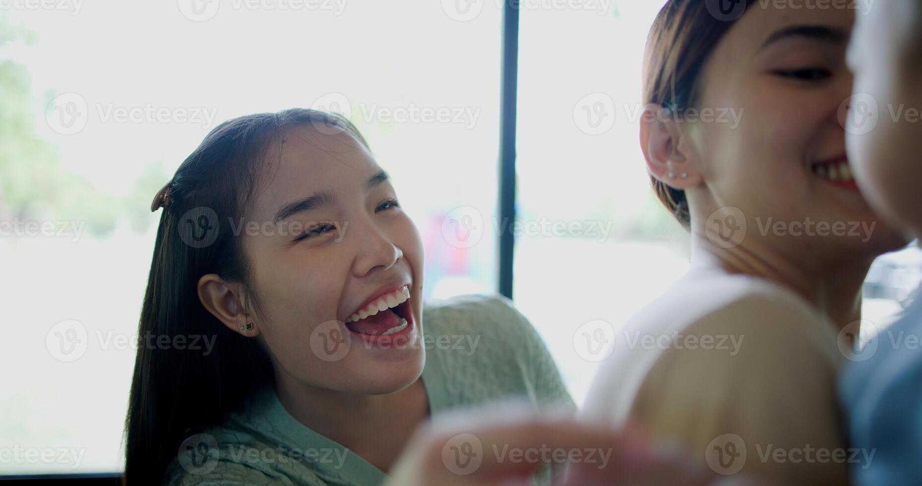 Selective focus, Two happy women having fun playing with a little boy in a coffee shop. Family enjoying time together. Happy lifestyle. photo