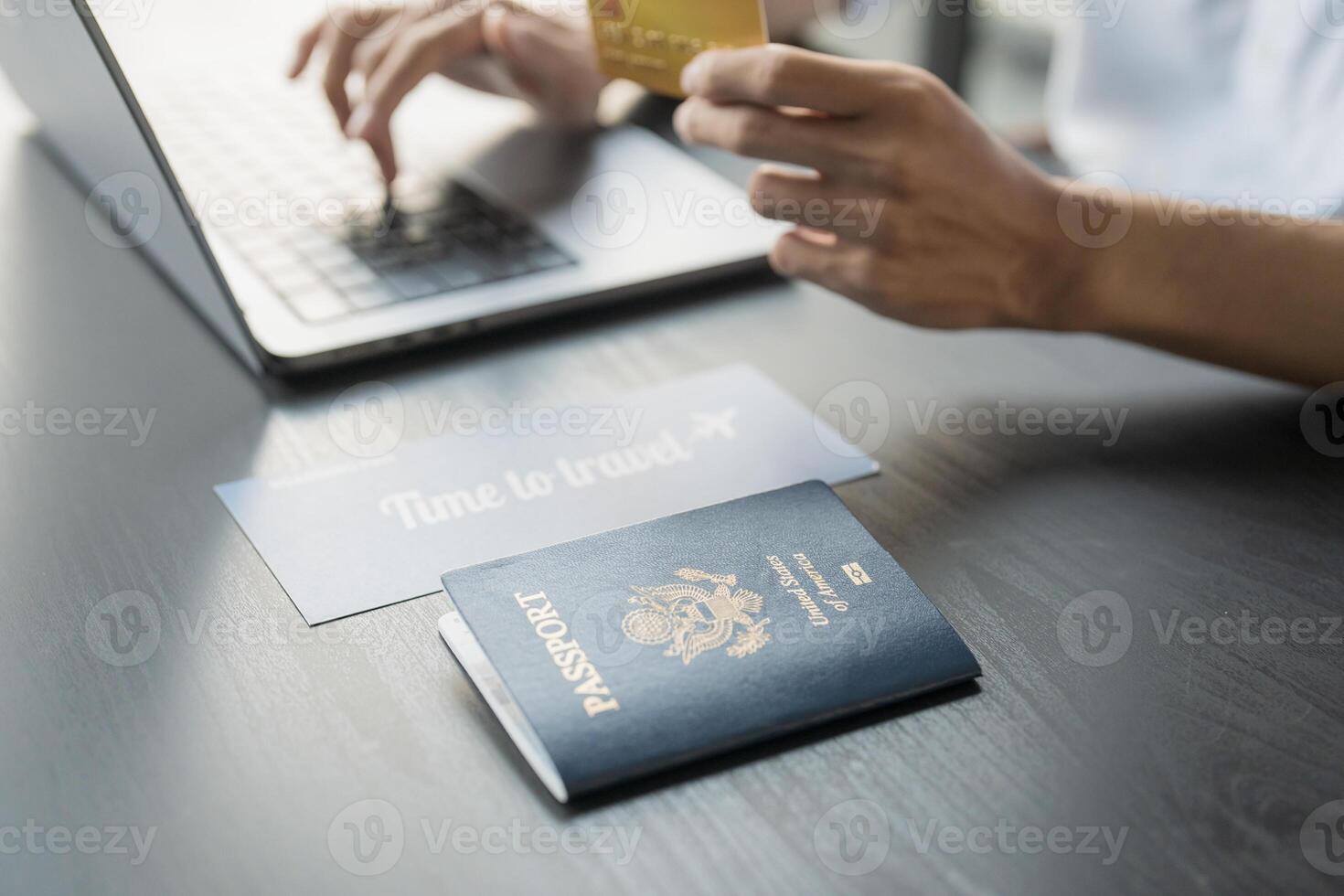 Hand Man Online booking and buying plane tickets using laptop phone and credit card Planning trip travel vacation with passport and ticket photo