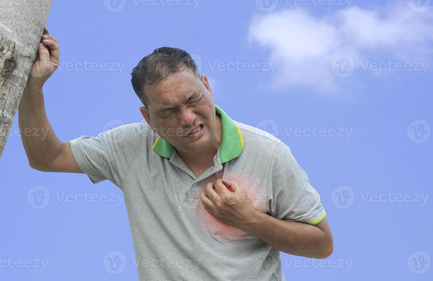 Asian mature man is suffering sharp chest pain while walking in outdoor area, red spot around painful area photo