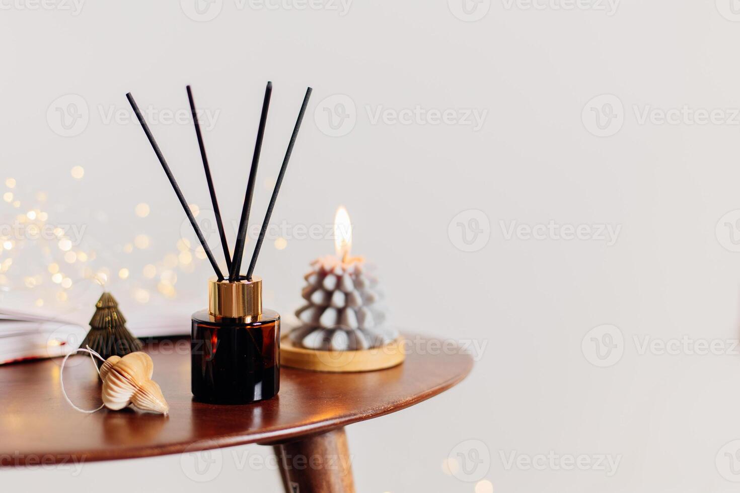 Home aroma fragrance diffuser and burning candles shape of tree on wooden table in the bedroom. Interior elements. Christmas and Winter decoration photo