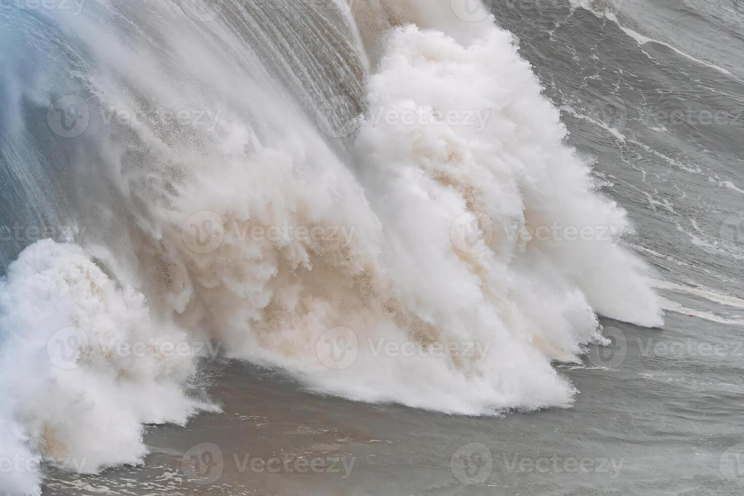 Huge wave crashing with dramatic foam and spray at Nazare in Portugal photo