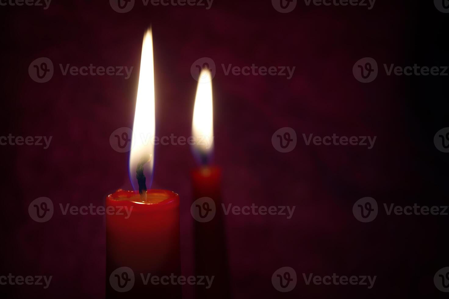 Red candles with flickering flame against a textured dark background photo