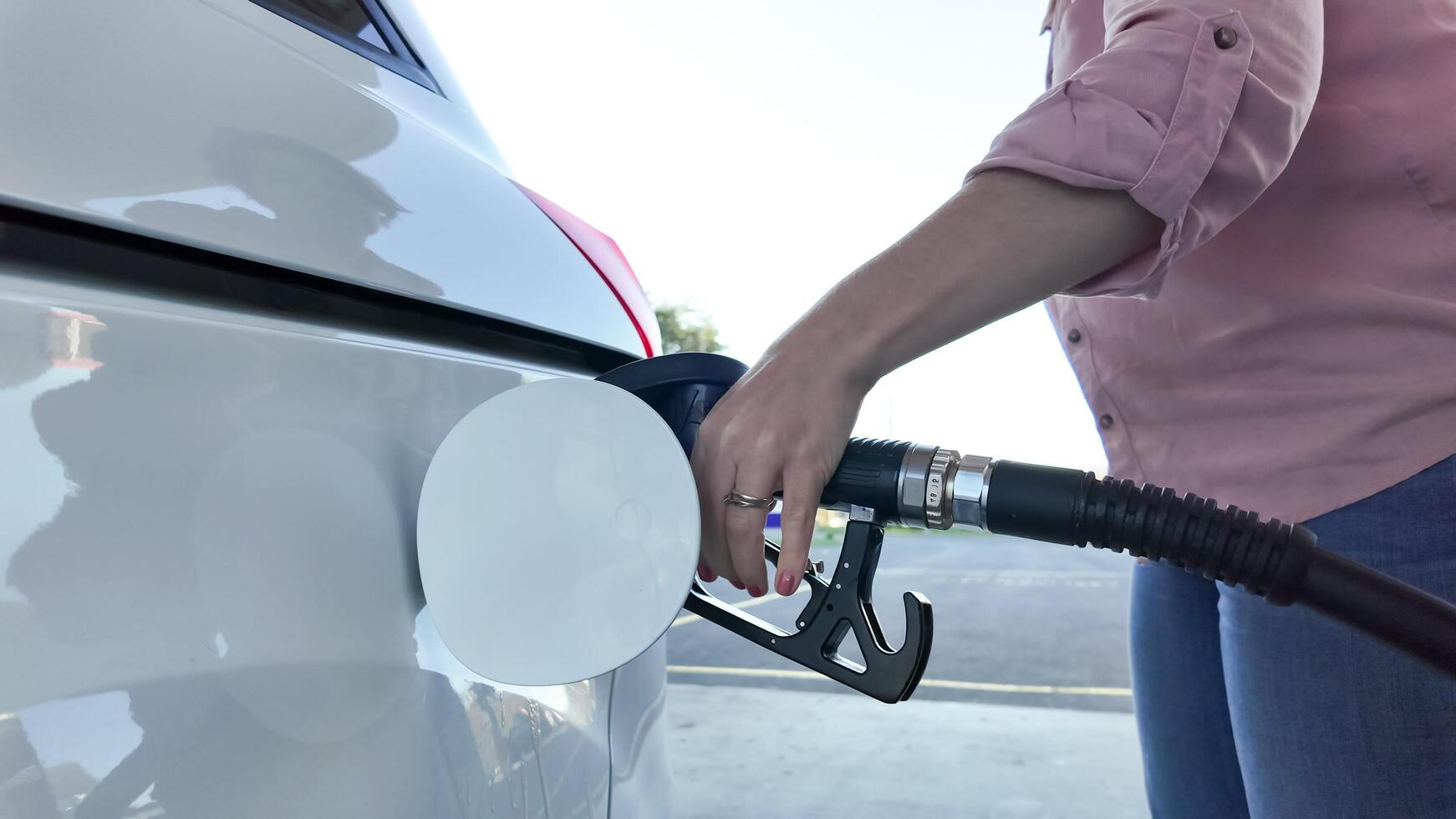 A person refuels a car at a gas station, highlighting the concept of rising fuel costs and travel preparation photo