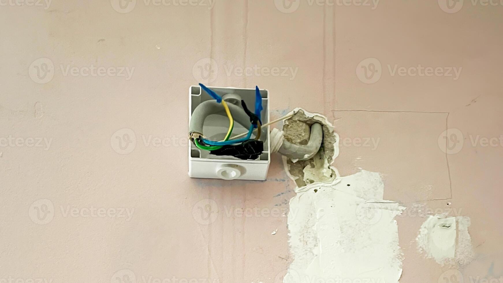 An exposed electrical junction box with colorful wires protruding from the wall, related to home maintenance and electrical safety photo