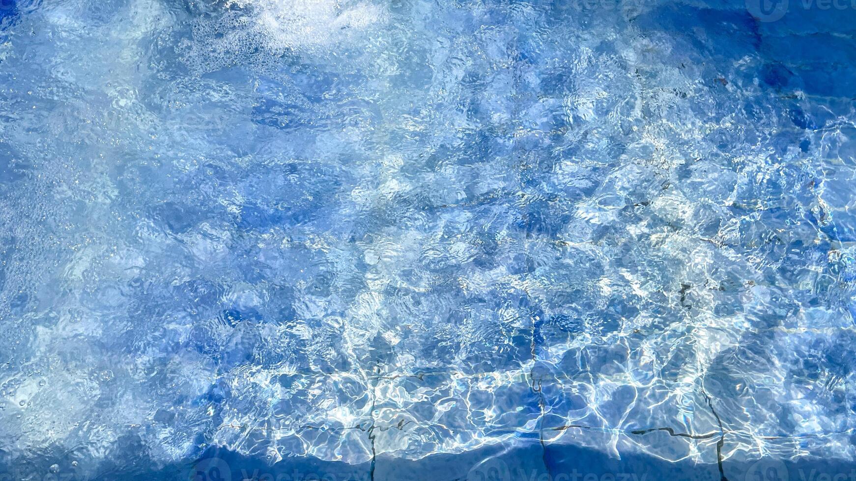 Clear blue water ripples in a sunlit swimming pool, ideal for summer relaxation and vacation themed designs photo