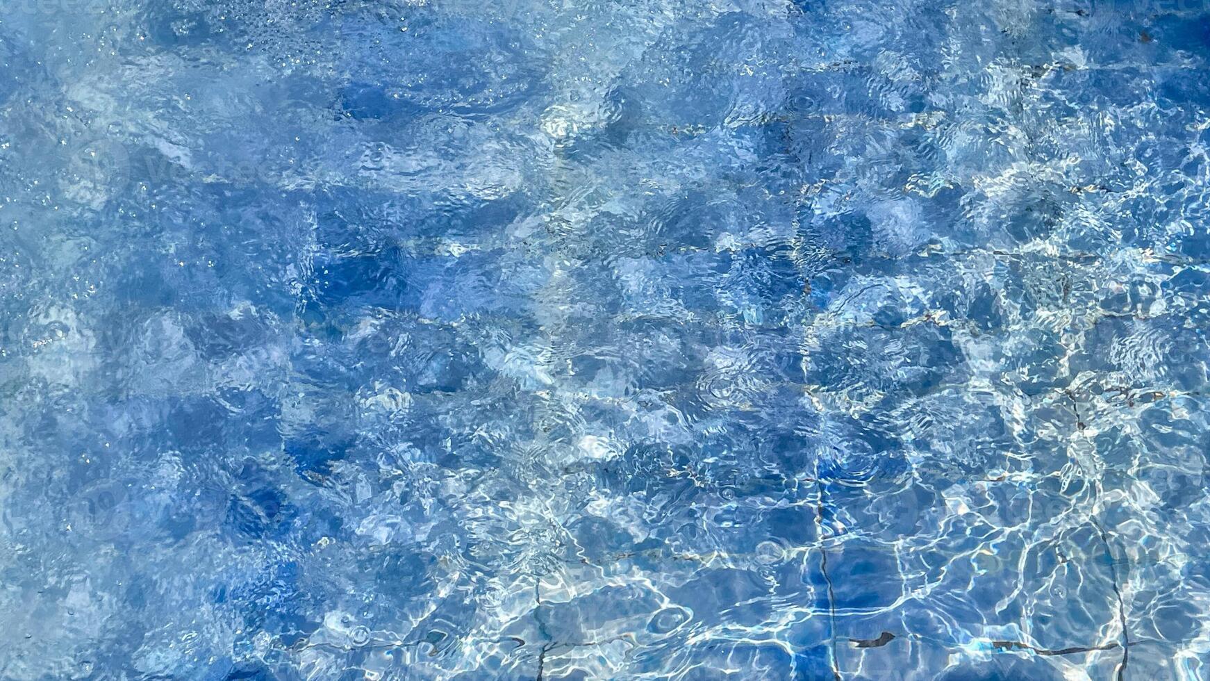 Clear blue pool water sparkles under sunlight, perfect for summer themes, vacation relaxation, and promoting tranquility and refreshment photo