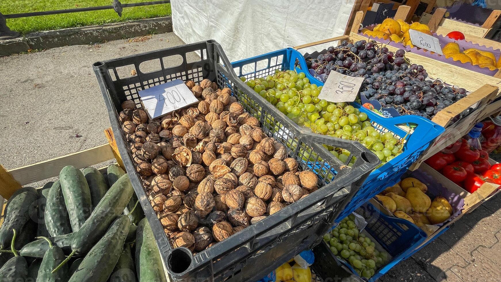 A vibrant farmers market stall features fresh cucumbers, walnuts, grapes, and pears, emphasizing sustainable local produce and healthy eating photo