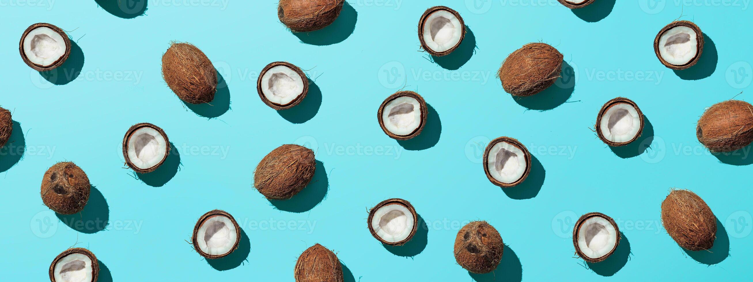 Creative layout of coconuts half on blue background. Tropical pattern, top view or flat lay. Hard light pop art minimal summer background. Horizontal banner photo