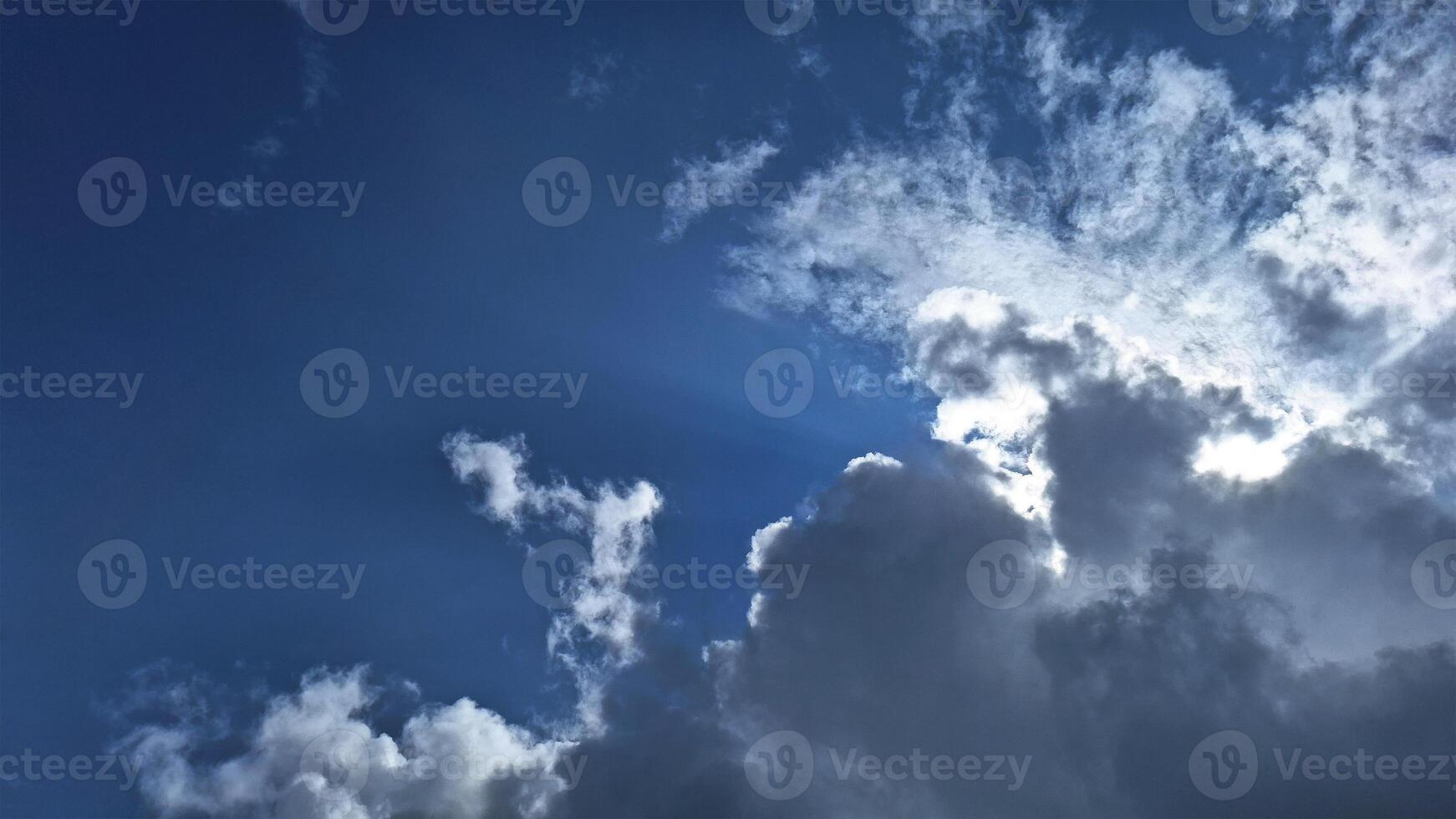 Sunlight emerging from behind dark clouds in the blue sky. This lighting effect gives a dramatic and magical touch to the scene, showcasing the power and beauty of nature. photo