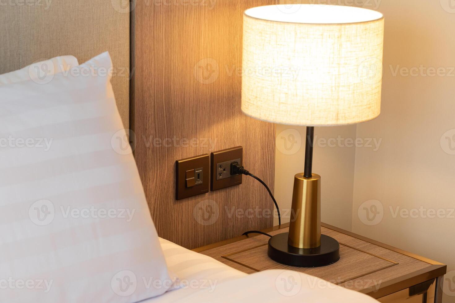 Bedroom setting including bedside table with lamp. photo