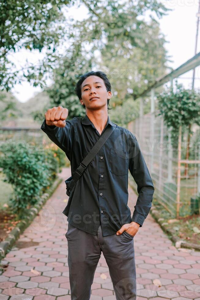 Southeast Asian man raising his fist with a determined expression photo
