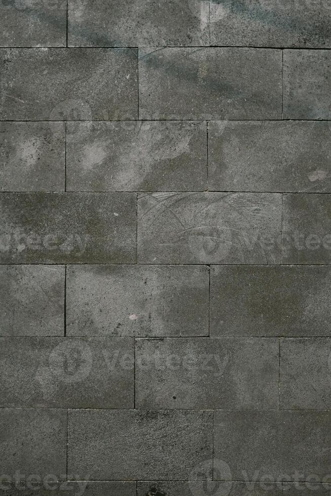 Textured grey stone wall with rectangular tiles, showing subtle patterns and weathered details. photo