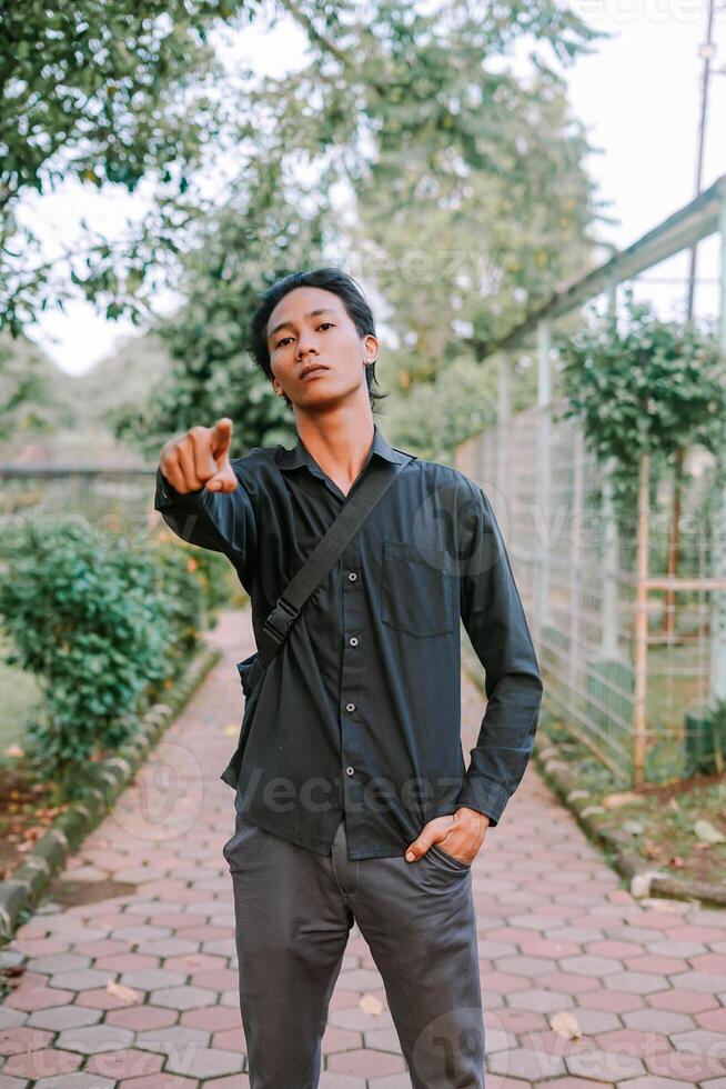 Southeast Asian Southeast Asian man pointing forward with a confident expression. Ideal for themes of direction, guidance, or focus.. photo