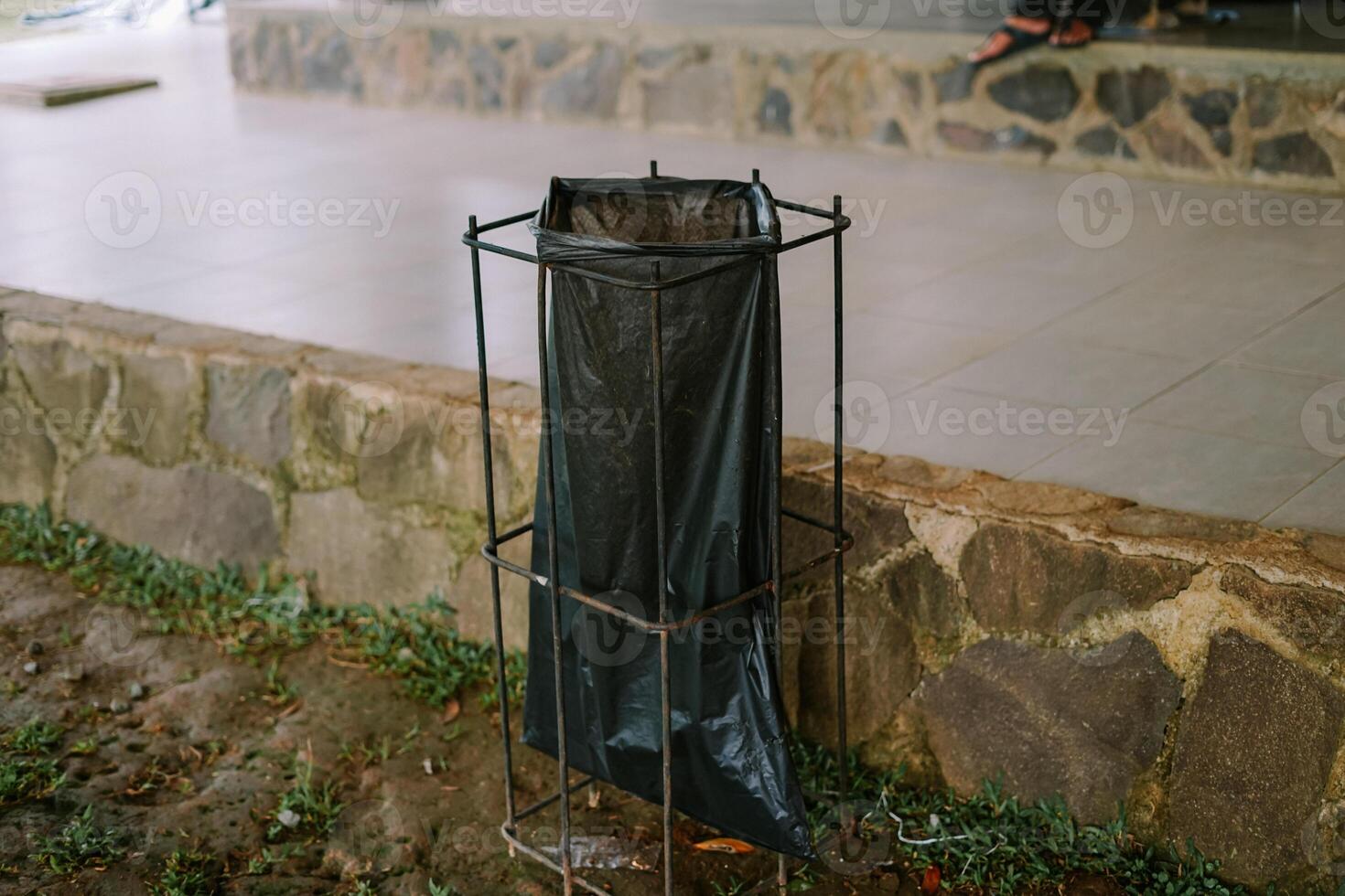 Outdoor trash bin with black liner on a natural ground background. photo