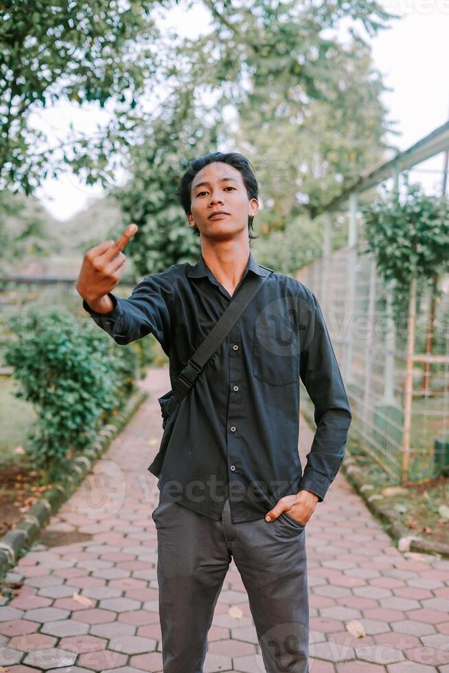 Southeast Asian man making a bold gesture with his middle finger, showing defiance photo