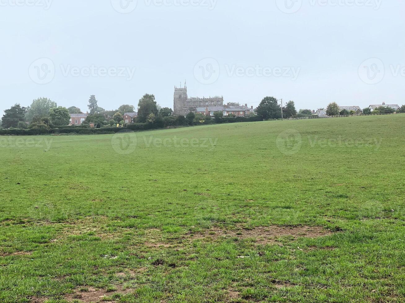 A field with a large grassy area and a church in the background photo