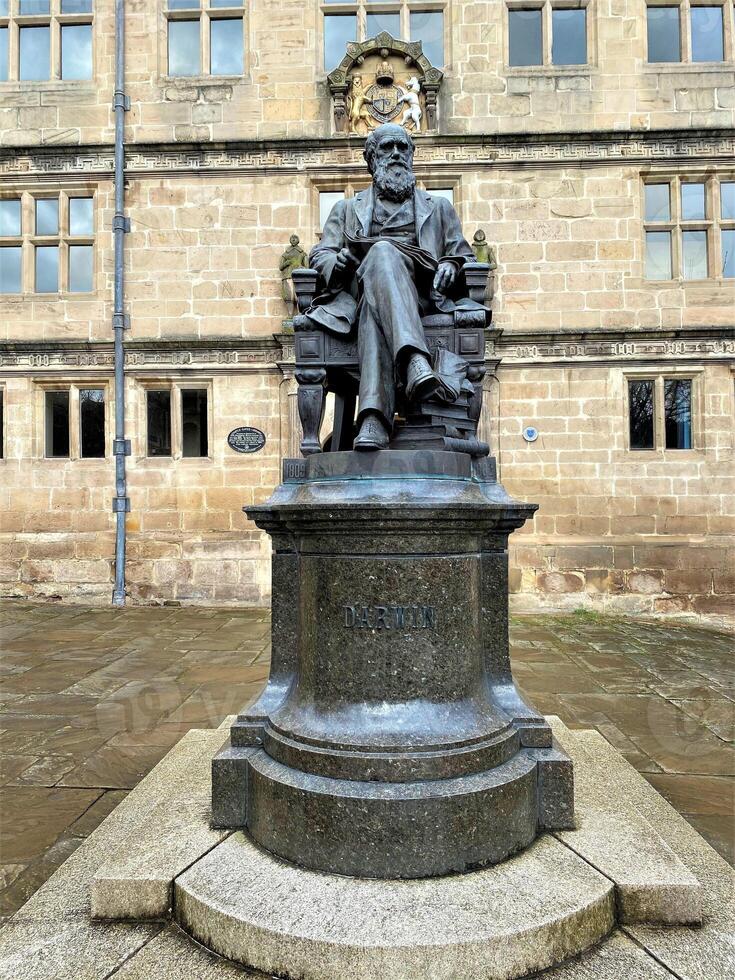 A statue of a man sitting on a chair in front of a building photo