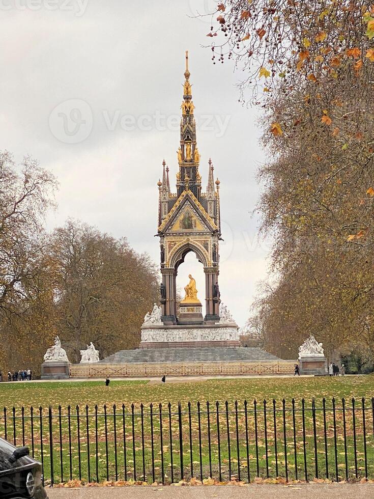 A statue of a man sitting on a bench in front of a park photo