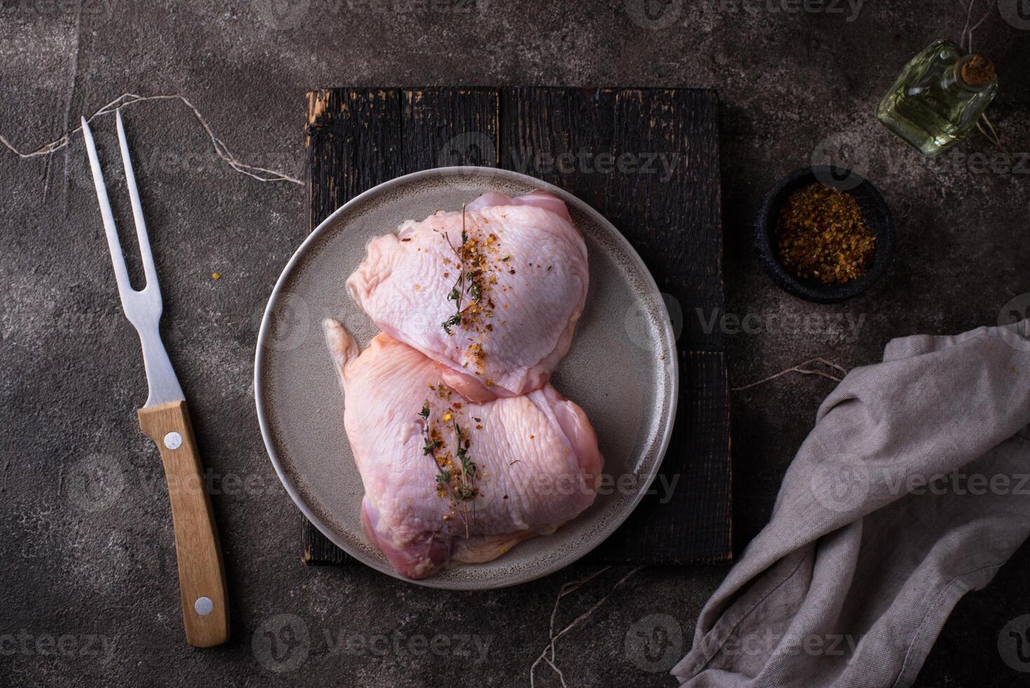 Raw chicken thighs on dark kitchen table photo