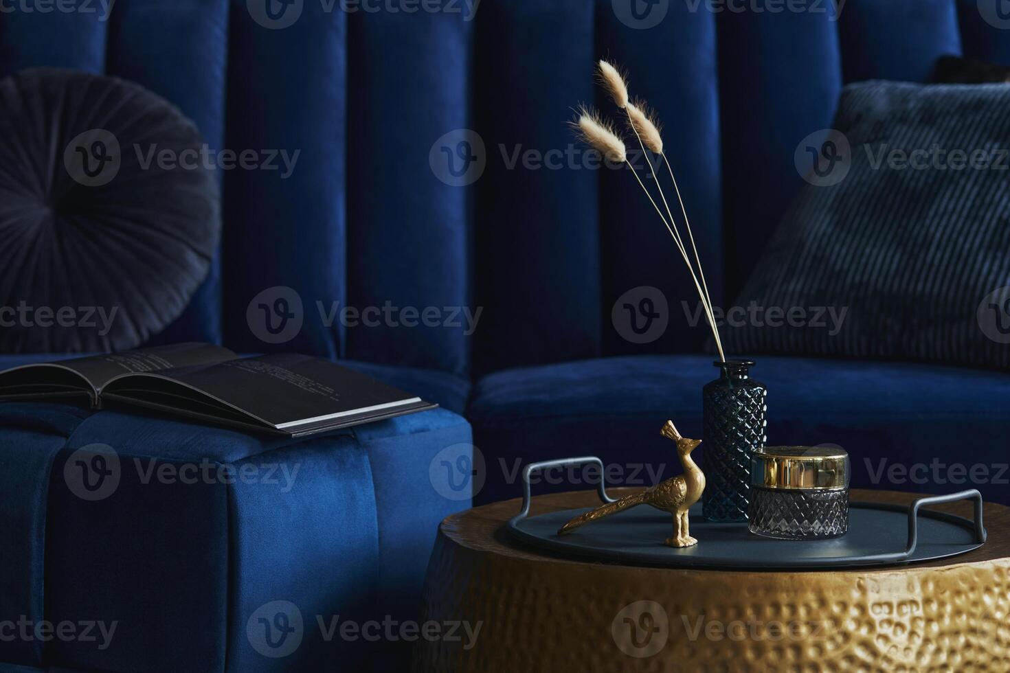 Stylish close up on the elegant details in the glamour living room interior. Golden peacock and creative personal accesories. Dark blue sofa on the background. Template. Copy space. photo