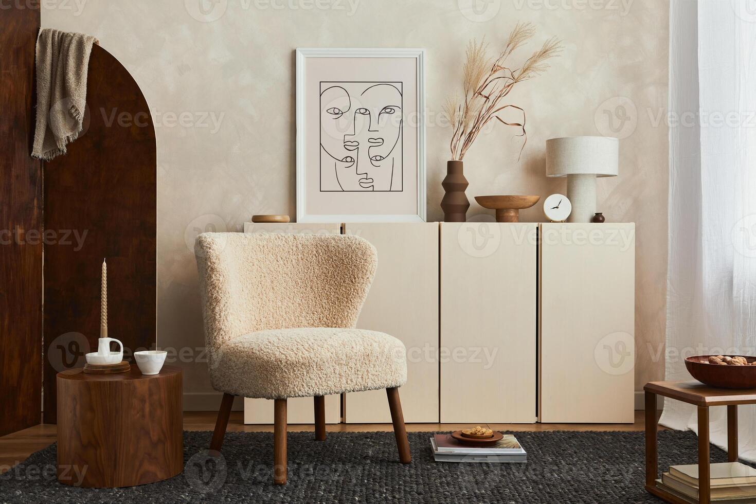 Creative composition of cozy living room interior design with mock up poster frame, fluffy armchair, folding screen, coffee table, commode and personal accessories. Modern style. Template. photo