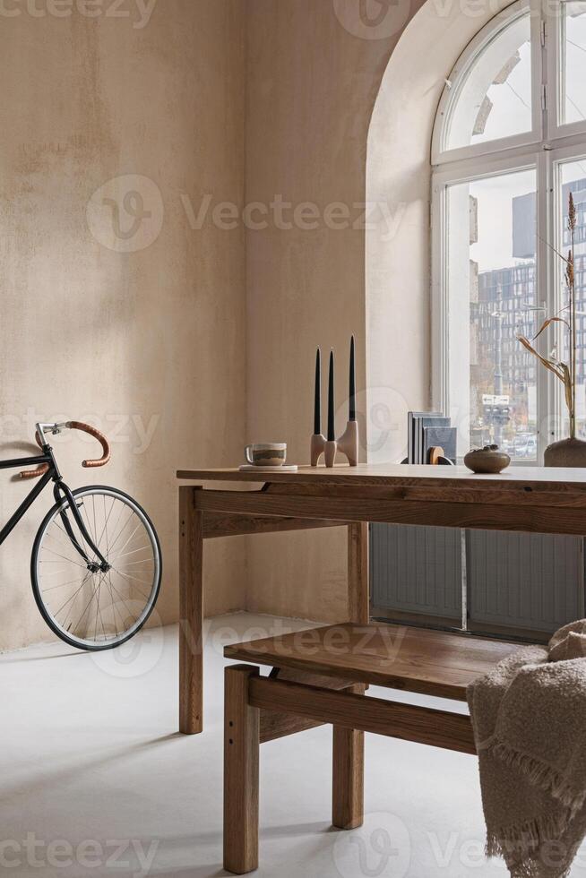 Stylish interior design of dining room with wooden dining table, bench and beautiful personal accessories. Modern home decor. Structure wall. Rustic minimalistic inspiration. Template photo