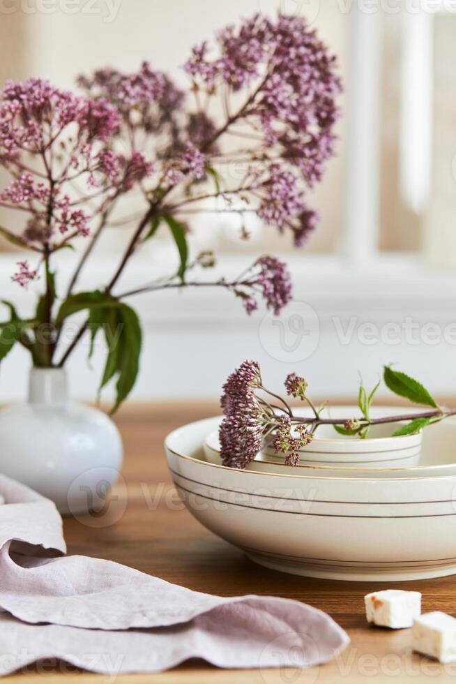 Elegant composition of classy dining room interior design with rustic table, beautiful porcelain, flowers and kitchen accessories. Beauty in the details. Template. photo