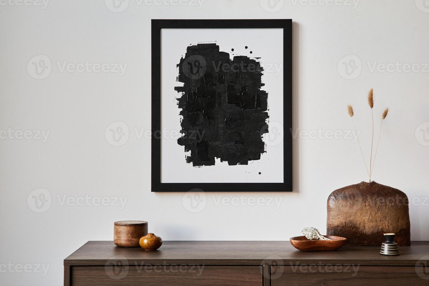 Creative composition of modern living room interior design with mock up poster frame, brown commode, vases and personal accessories. White wall. Template photo