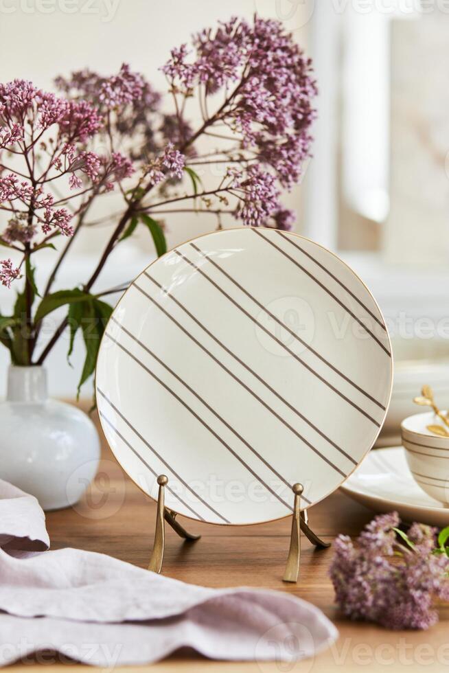 Elegant composition of classy dining room interior design with rustic table, beautiful porcelain, flowers and kitchen accessories. Beauty in the details. Template. photo