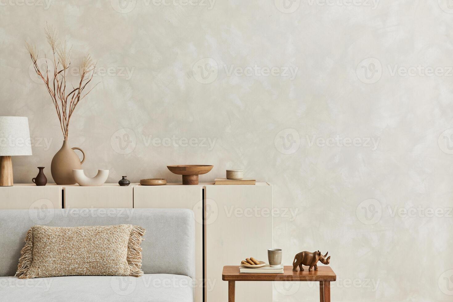 Creative composition of stylish living room interior with copy space, grey sofa, beige commode, clay vases and stylish personal accessories. Pastel neutral colours. . photo