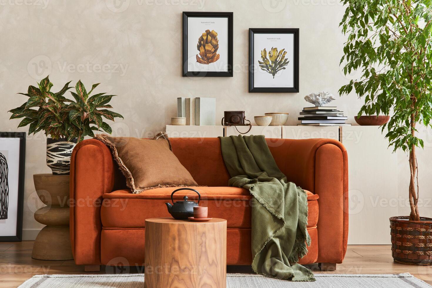 Creative composition of stylish living room interior with mock up poster frames, orange sofa, beige commode, coffee table and stylish personal accessories. Plants lover space. . photo