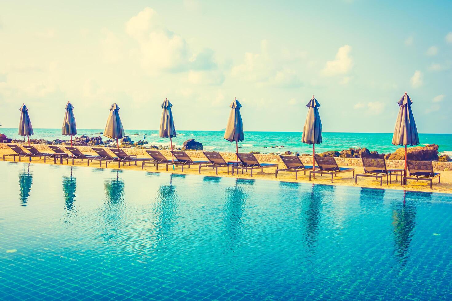 A long pool with umbrellas and chairs near the ocean photo