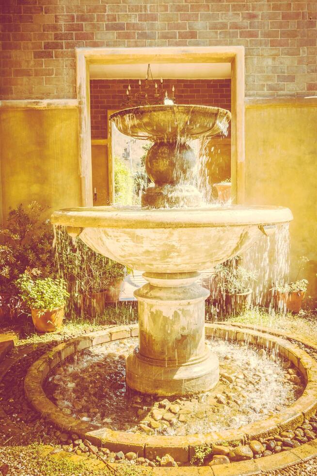 A fountain in a courtyard with a stone wall photo