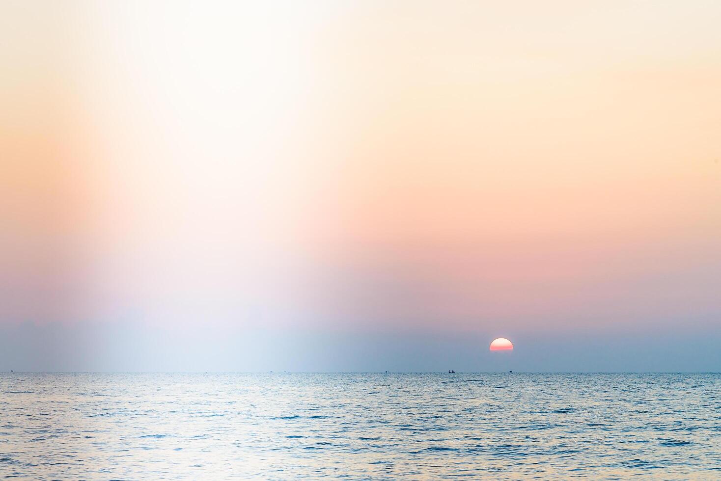 A man is standing on a beach with a sailboat photo