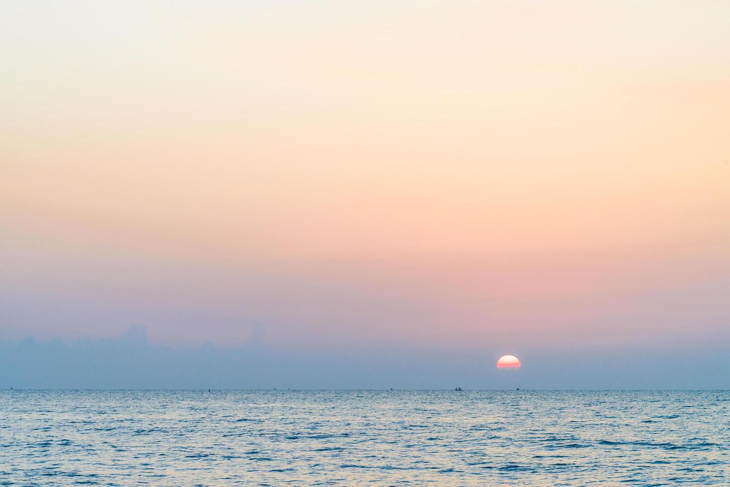 A person flying a kite in the ocean at sunset photo