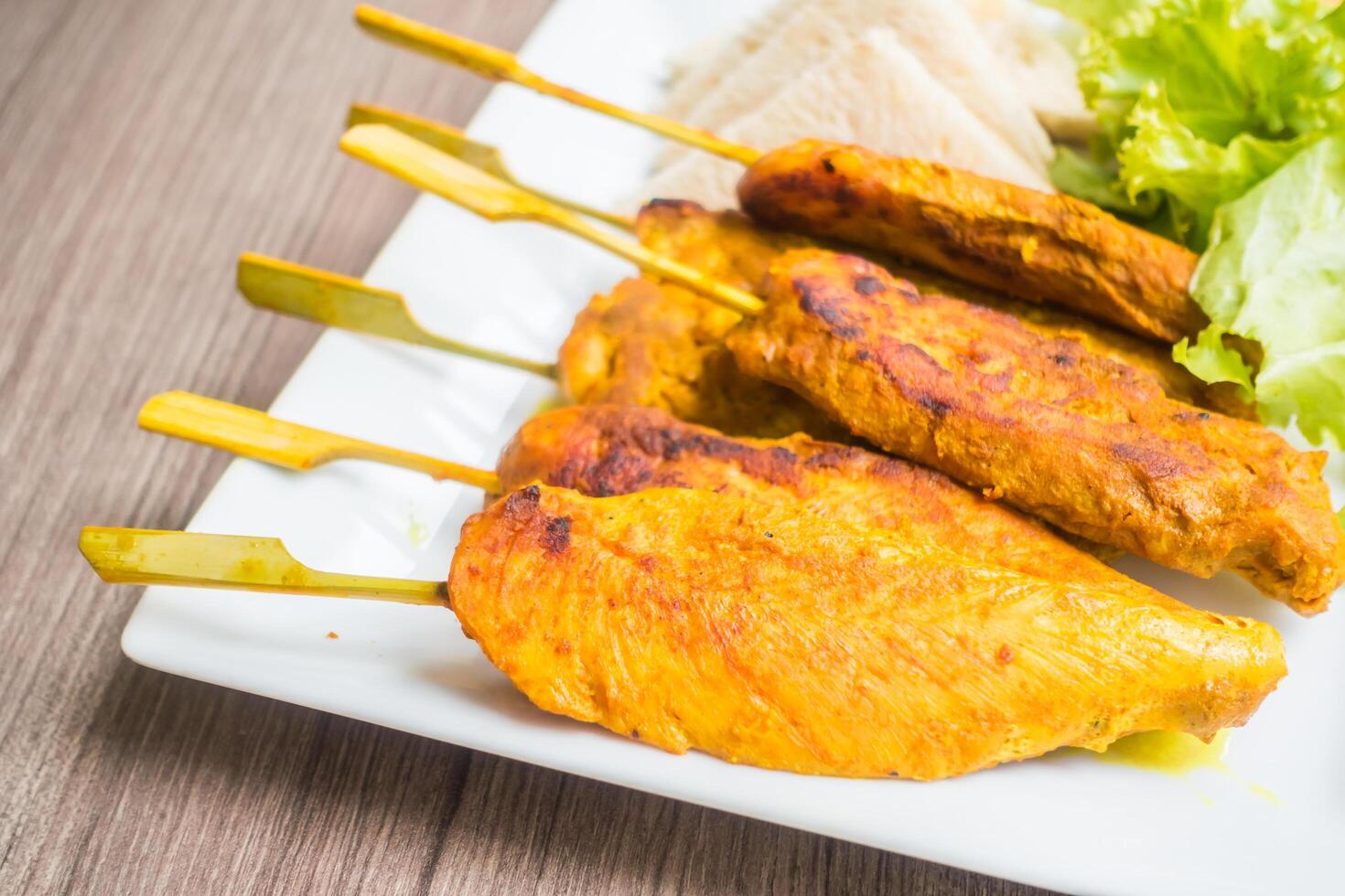 A plate with chicken skewers and salad photo