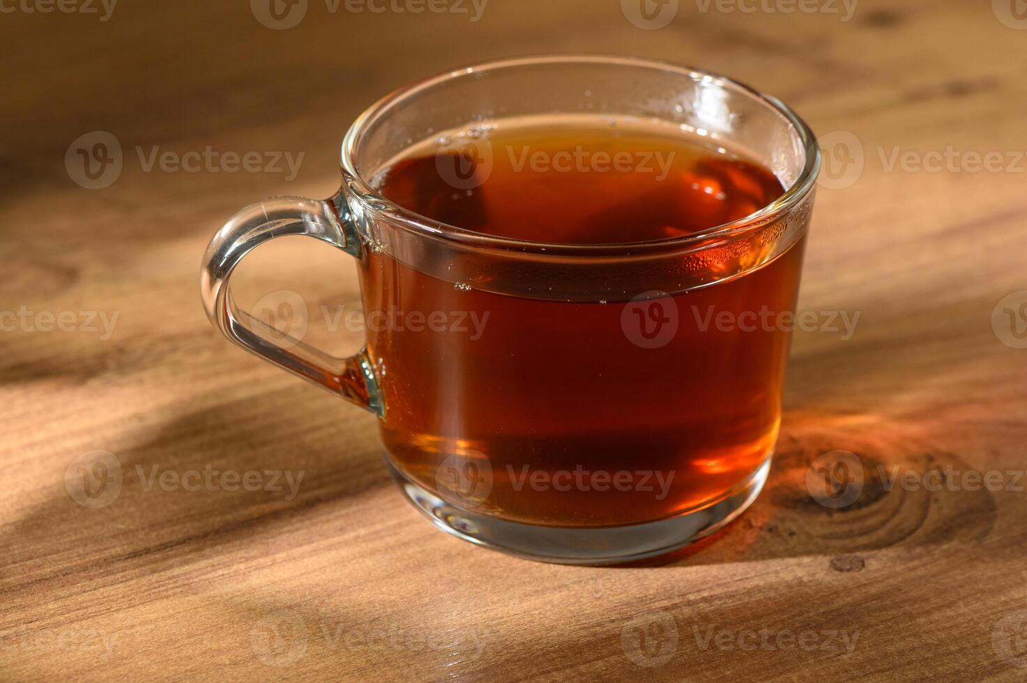 Warm cup of freshly brewed herbal tea resting on a rustic wooden table in soft afternoon light photo