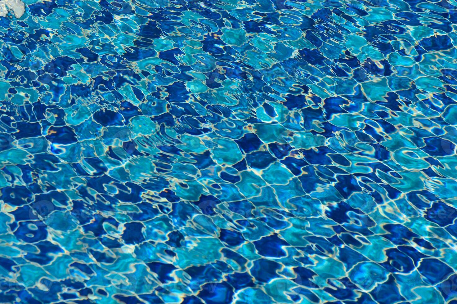 Glittering blue water ripples create a mesmerizing pattern on a sunny afternoon at the pool photo
