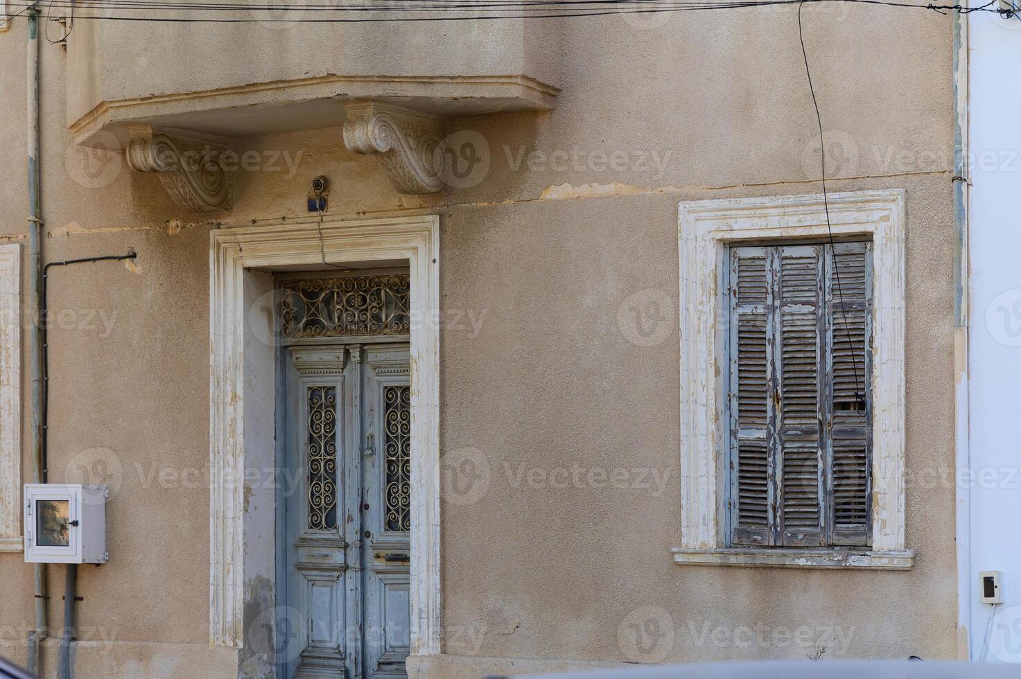 Charming weathered building facade with detailed wooden door and shutters in a quaint village setting photo