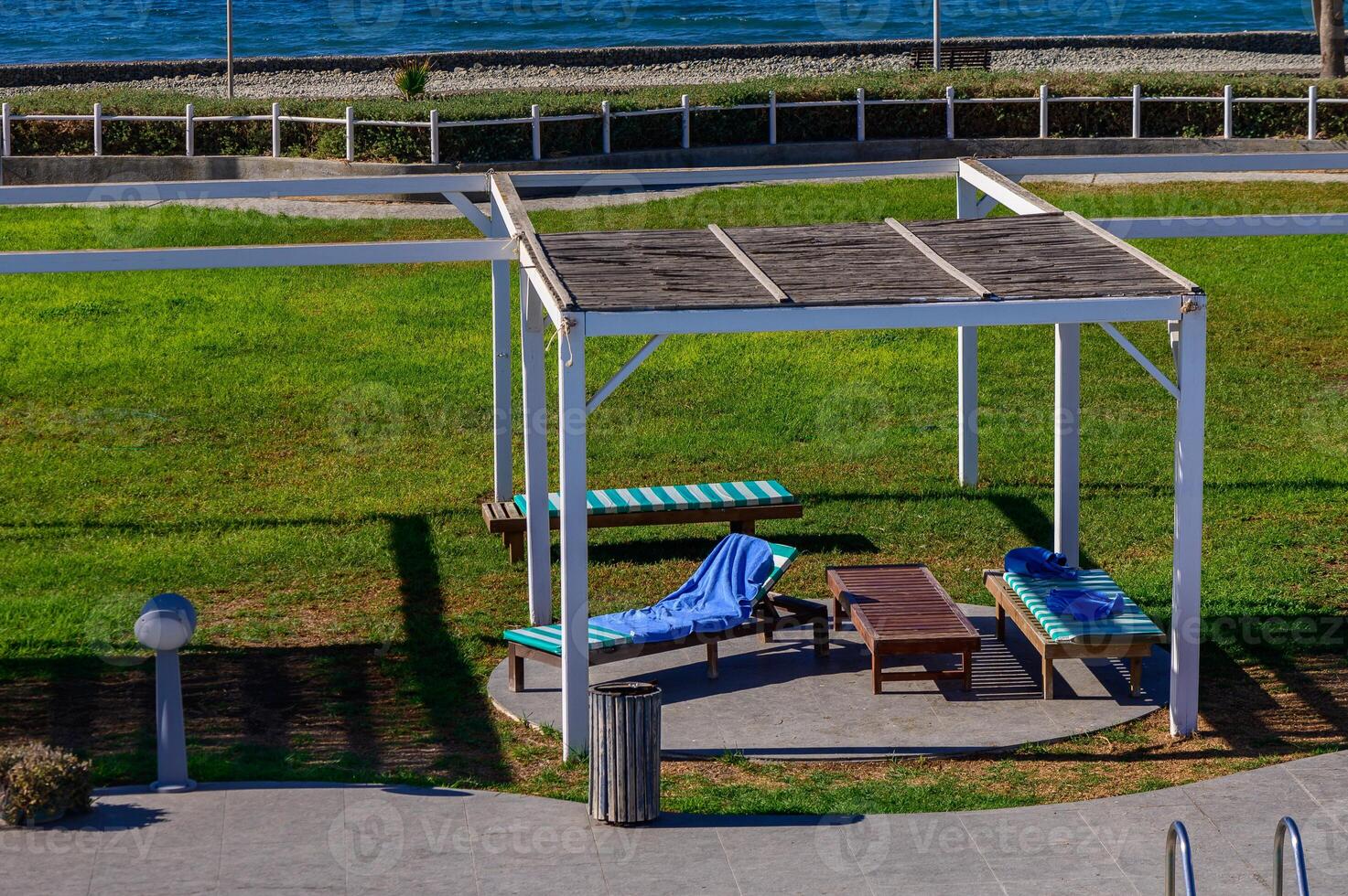Relaxing under a wooden gazebo on a sunny day by the beach with lounge chairs and ocean views photo