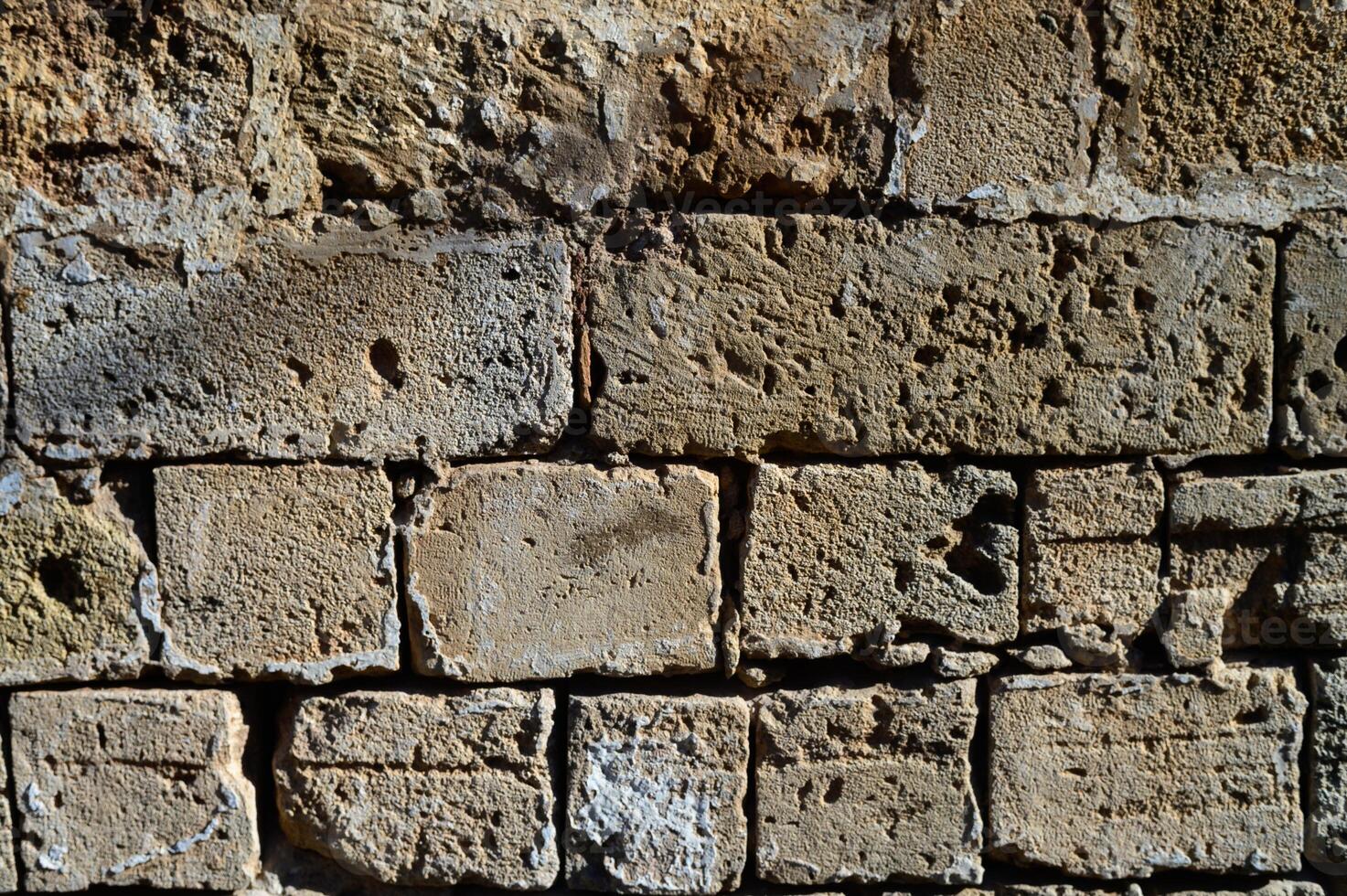 Weathered stone wall with texture and character in a rustic setting illuminated by soft natural light photo