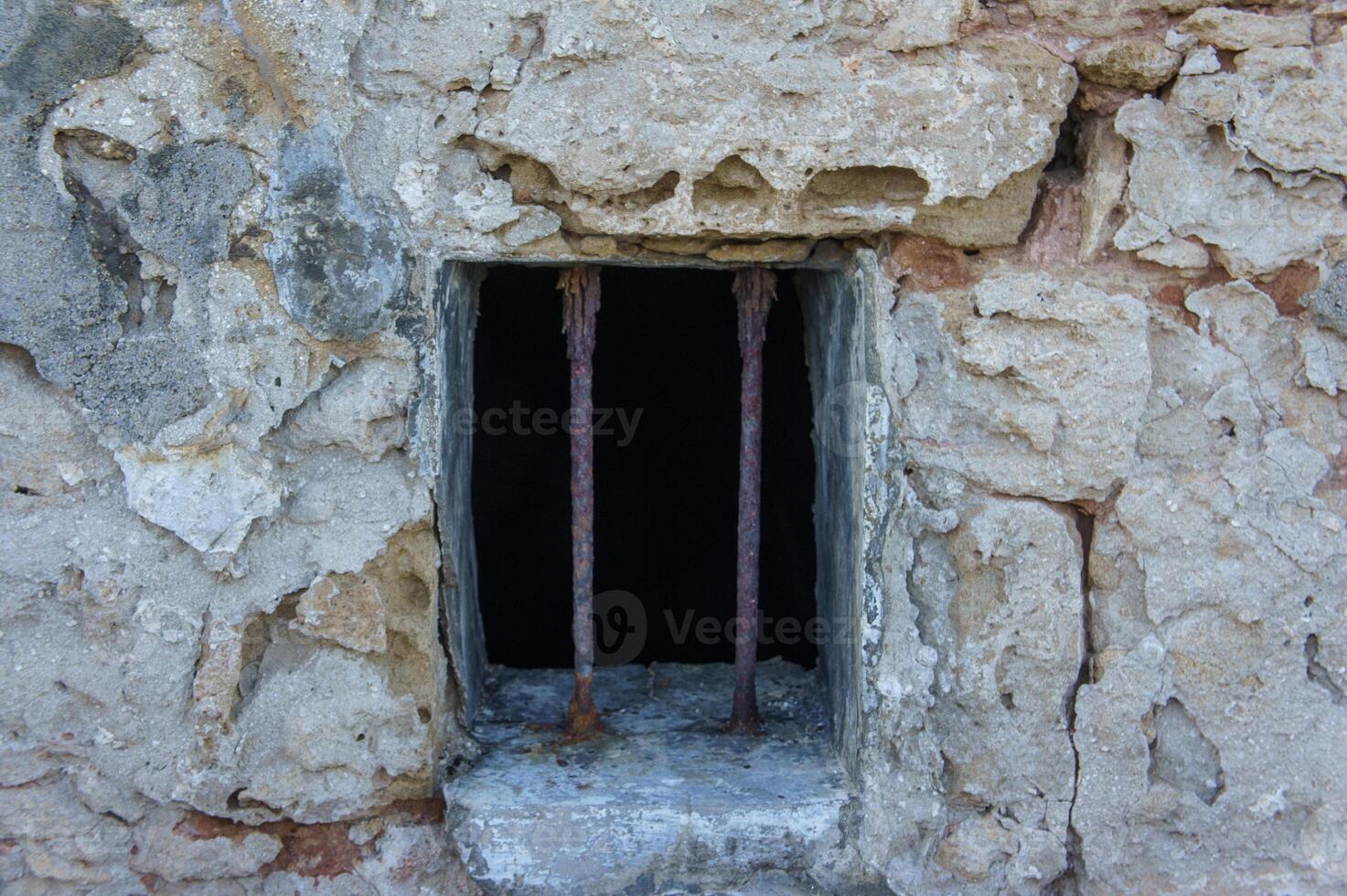 Old stone prison window with rusty bars in a historic building. photo