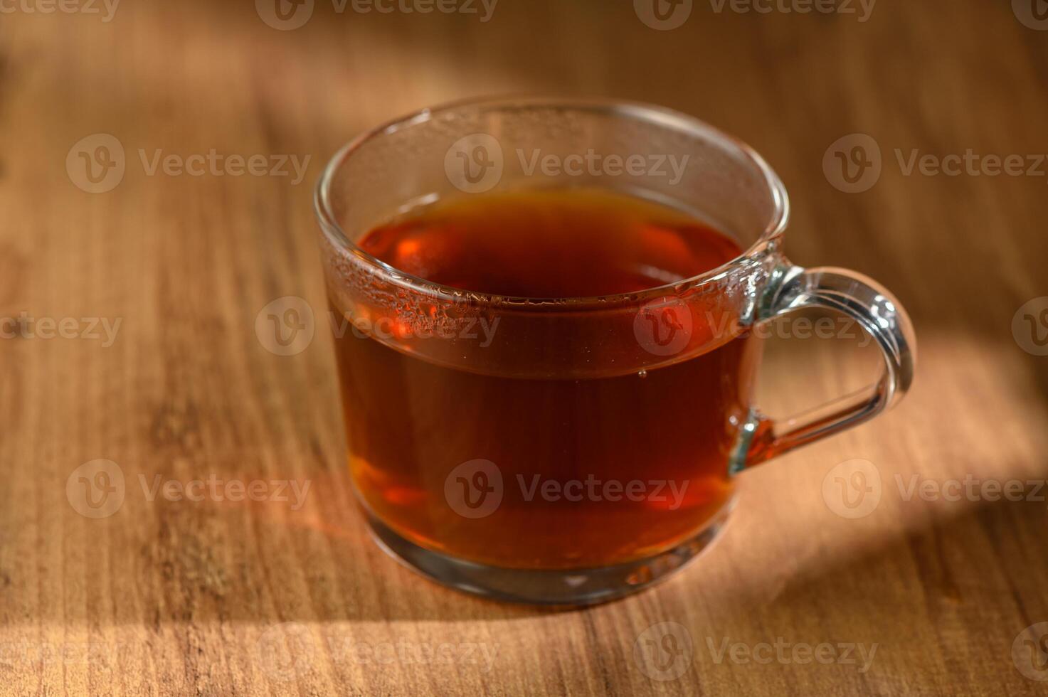 Cozy afternoon tea in a clear glass mug on a rustic wooden table inviting warmth and relaxation photo