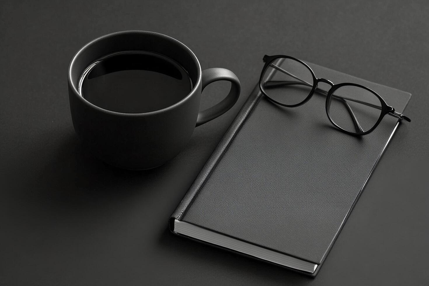 A dark workspace with a black coffee mug and glasses beside an open notebook during evening hours photo