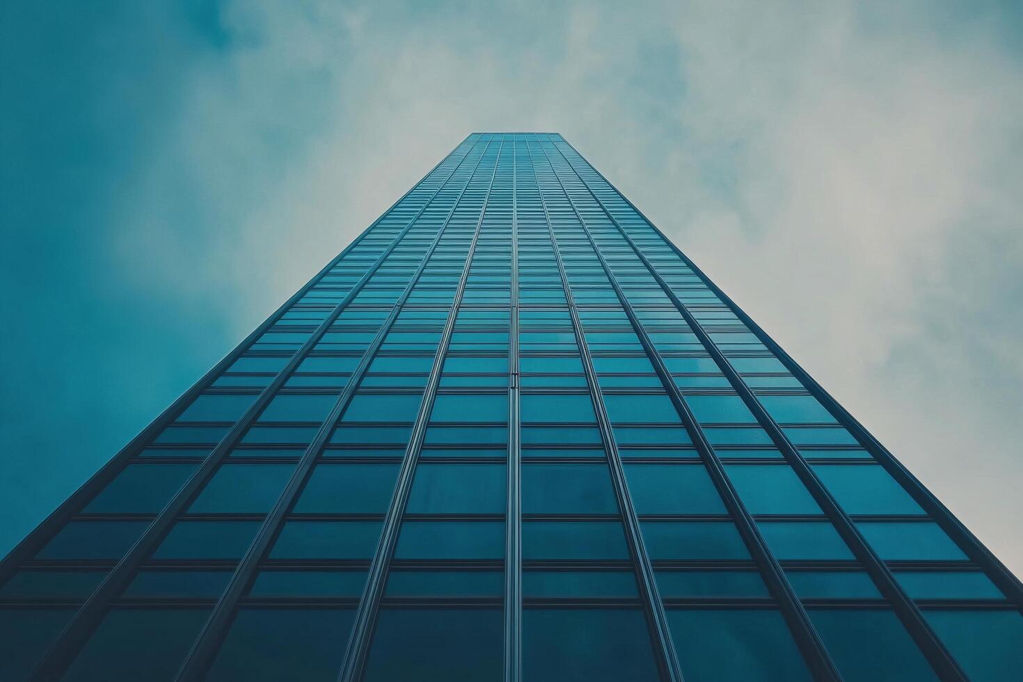 A towering skyscraper rises against a clouded sky in an urban landscape during daylight hours photo