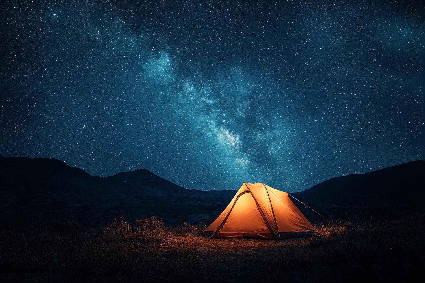 Bright yellow tent under a starry night sky in a remote mountain valley photo