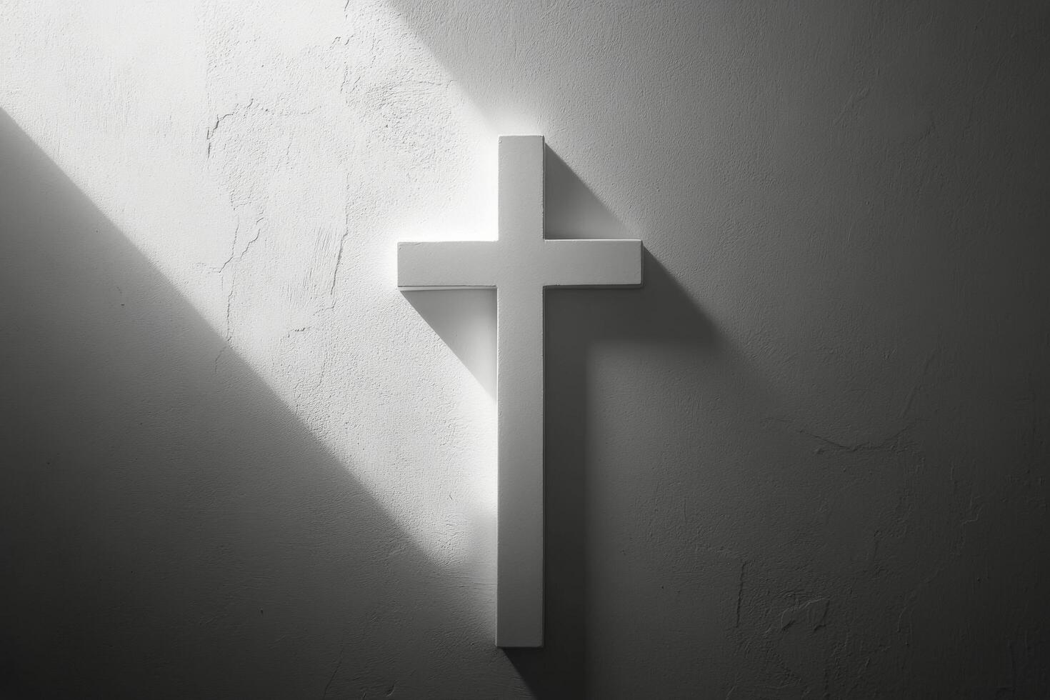 A white cross casting shadows on a textured wall in soft light during the early morning hours photo